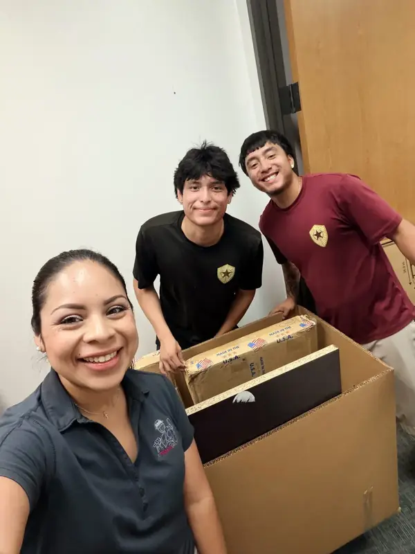 Tiffany, Adrian and Hector Jr smiling beside packed boxes during an office move