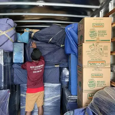 Fully loaded truck with wrapped furniture and labeled moving boxes strapped in place