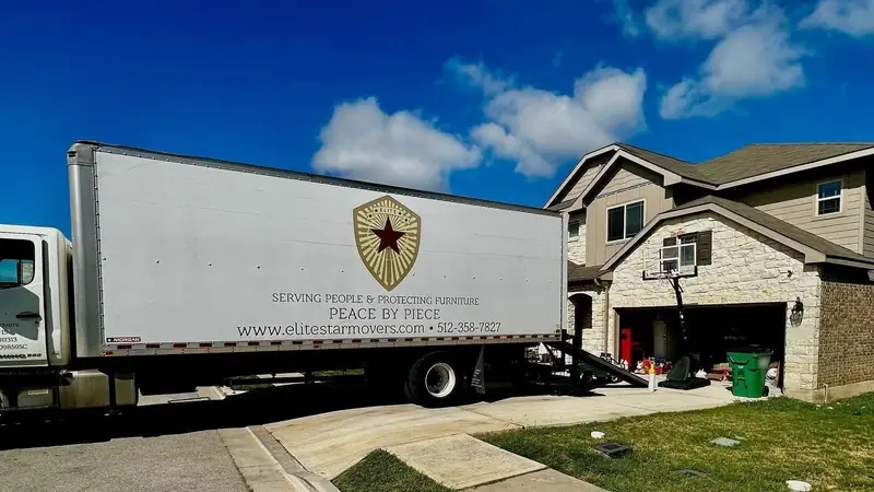 Elite Star Movers box truck with the Peace by Piece logo backed up to a home on moving day