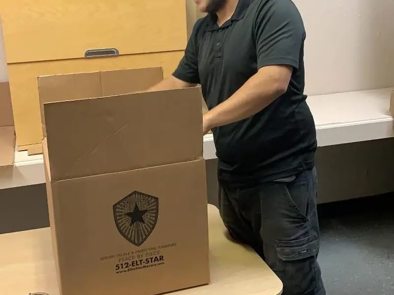 Mover packing an Elite Star branded box on a table